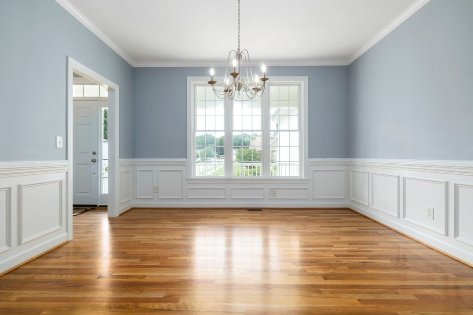 Room with white wainscoting, crown molding and a hardwood floor
